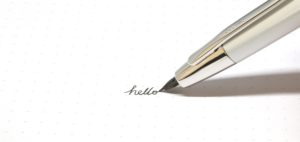 A silver pen writes hello on paper