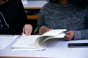 2 students read through a pile of papers together