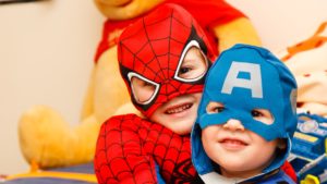 Two small children dressed in Spiderman and Captain America costumes