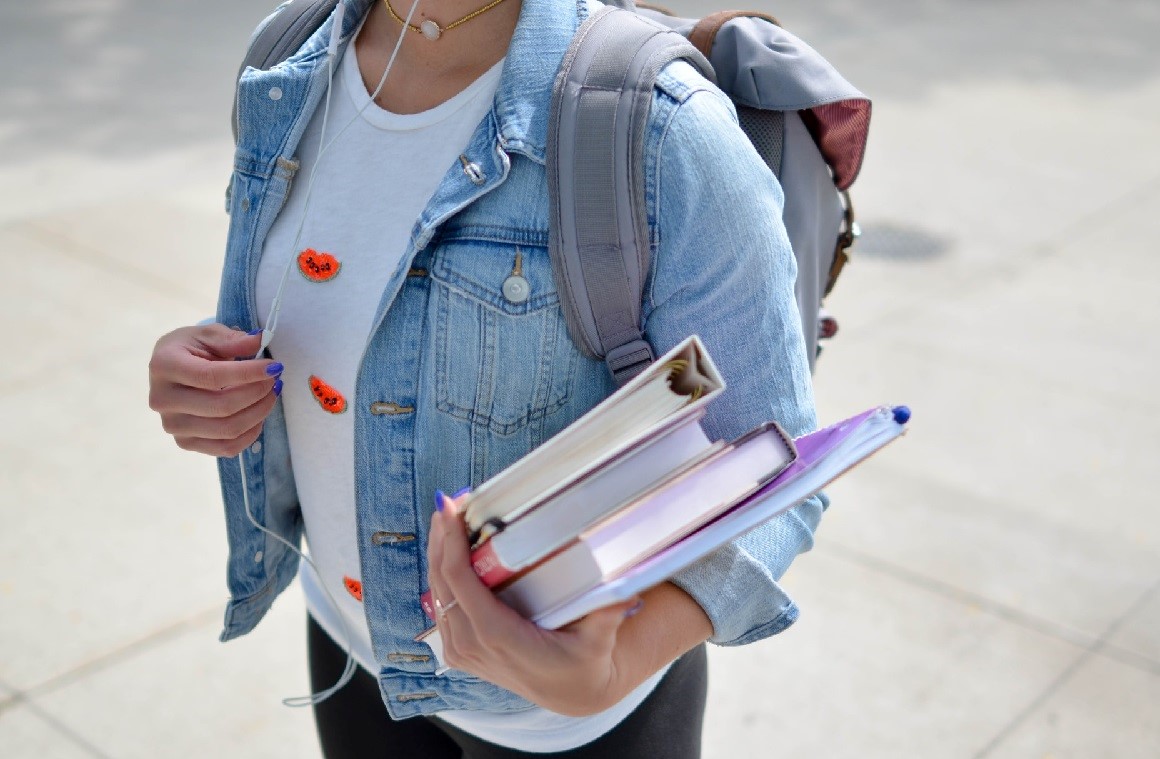 A young woman carries books