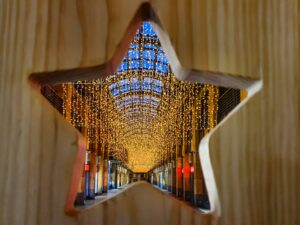 A star shaped hole in a door shows a corridor decorated with sparkling lights